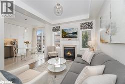 Living room featuring a glass covered fireplace, light wood-style flooring, and a raised ceiling - 