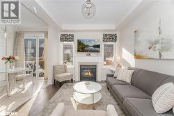 Living area with wood-type flooring, a glass covered fireplace, and a tray ceiling - 