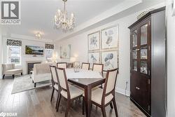 Dining area featuring a raised ceiling, a warm lit fireplace, wood-type flooring, and a chandelier - 