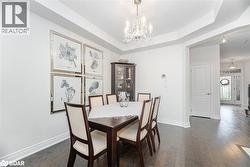 Dining space featuring a raised ceiling, a chandelier, and dark wood-type flooring - 