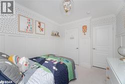 Bedroom featuring ornamental molding, light carpet, a wainscoted wall, wallpapered walls, and a decorative wall - 