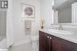 Full bath with light tile patterned floors, vanity, and shower / bath combo with shower curtain - 
