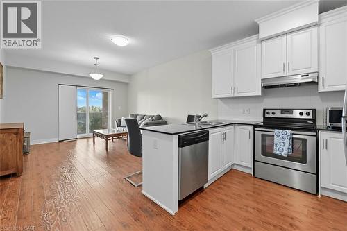 Kitchen featuring stainless steel appliances, a peninsula, tasteful backsplash, white cabinets, and light wood-type flooring - 8111 Forest Glen Drive Unit# 524, Niagara Falls, ON - Indoor Photo Showing Kitchen With Stainless Steel Kitchen With Double Sink