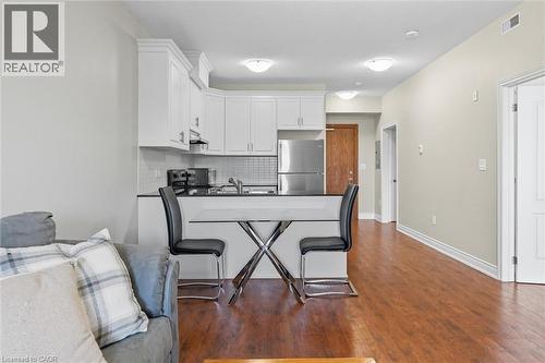 Kitchen with a peninsula, freestanding refrigerator, tasteful backsplash, white cabinets, and dark wood-style flooring - 8111 Forest Glen Drive Unit# 524, Niagara Falls, ON - Indoor