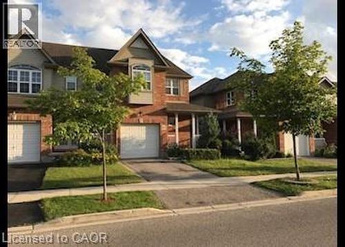 View of front facade with driveway, a garage, brick siding, and a front lawn - 567 Chablis Drive, Waterloo, ON - Outdoor With Facade