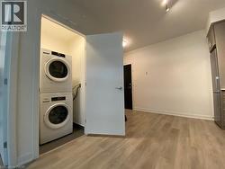 Washroom with light wood-style floors and stacked washing machine and dryer - 