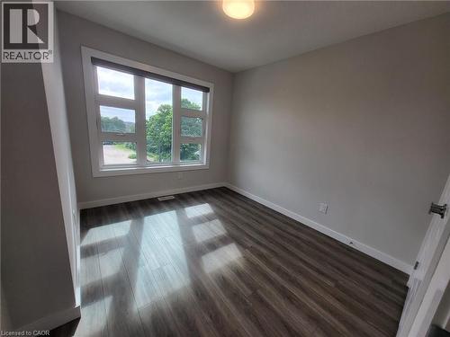 Unfurnished room featuring dark wood-style floors and baseboards - 118 Gravel Ridge Trail Unit# A8, Kitchener, ON - Indoor Photo Showing Other Room
