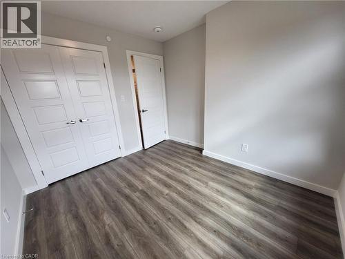 Unfurnished bedroom featuring a closet and dark wood-style flooring - 118 Gravel Ridge Trail Unit# A8, Kitchener, ON - Indoor Photo Showing Other Room