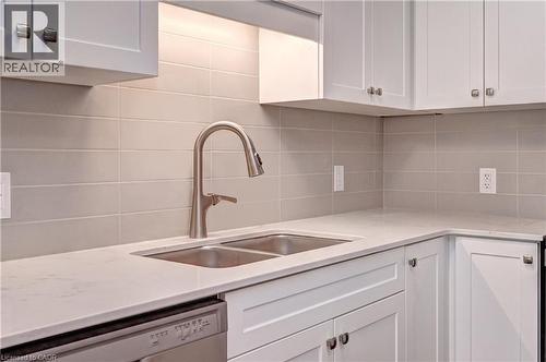 Kitchen with white cabinetry, dishwasher, decorative backsplash, and light stone counters - 118 Gravel Ridge Trail Unit# C17, Kitchener, ON - Indoor Photo Showing Kitchen With Double Sink
