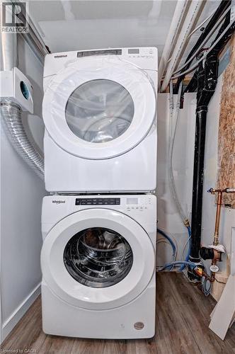 Washroom featuring stacked washer / drying machine and wood finished floors - 118 Gravel Ridge Trail Unit# C4, Kitchener, ON - Indoor Photo Showing Laundry Room