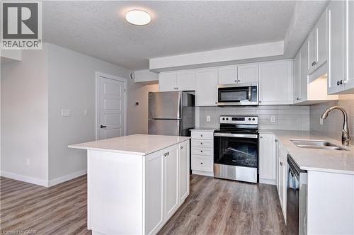 Kitchen with appliances with stainless steel finishes, white cabinetry, light stone counters, tasteful backsplash, and a textured ceiling - 118 Gravel Ridge Trail Unit# C4, Kitchener, ON - Indoor Photo Showing Kitchen With Stainless Steel Kitchen With Double Sink