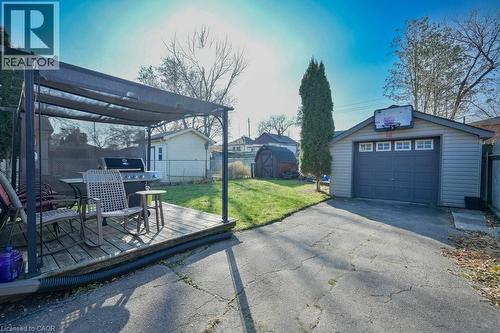 View of patio with asphalt driveway, a wooden deck, a detached garage, a storage shed, and a grill - 131 Elmwood Avenue, Cambridge, ON - Outdoor