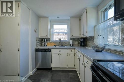 Kitchen featuring light countertops, black appliances, decorative backsplash, and white cabinetry - 131 Elmwood Avenue, Cambridge, ON - Indoor Photo Showing Kitchen