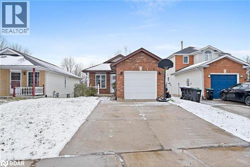 View of front facade featuring concrete driveway, brick siding, and an attached garage - 16 Bush Street, Collingwood, ON - Outdoor With Facade