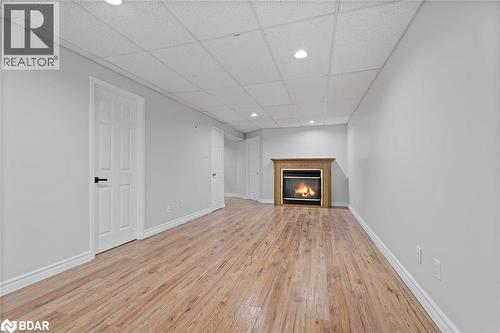 Unfurnished living room featuring a drop ceiling, a glass covered fireplace, recessed lighting, and light wood-style floors - 16 Bush Street, Collingwood, ON - Indoor With Fireplace