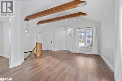 Unfurnished living room featuring wood finished floors and baseboards - 