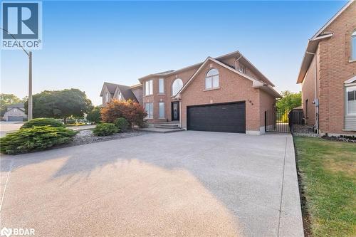 Traditional-style home with a gate, concrete driveway, brick siding, and a garage - 100 National Drive, Hamilton, ON - Outdoor