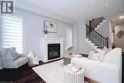 Living room with a glass covered fireplace, stairway, dark wood-type flooring, and recessed lighting - 