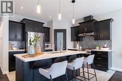 Kitchen featuring tasteful backsplash, stainless steel appliances, a breakfast bar area, dark cabinets, and recessed lighting - 