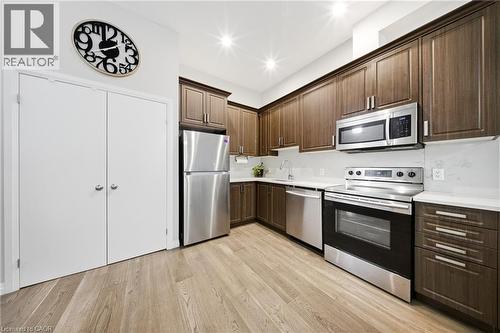 Kitchen with appliances with stainless steel finishes, dark brown cabinets, light wood-style floors, and recessed lighting - 85 Morrell Street Unit# 102A, Brantford, ON - Indoor Photo Showing Kitchen