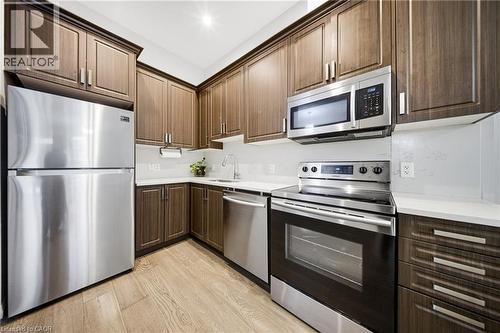 Kitchen with stainless steel appliances, light wood finished floors, and dark brown cabinetry - 85 Morrell Street Unit# 102A, Brantford, ON - Indoor Photo Showing Kitchen