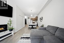 Living area with a warm lit fireplace, light wood-style floors, and a chandelier - 