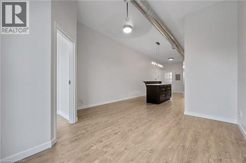 View from the far side of living room looking down the length of apartment. Storage closet with window to the left - 31 Main Street Unit# 301, Cambridge, ON - Indoor Photo Showing Other Room