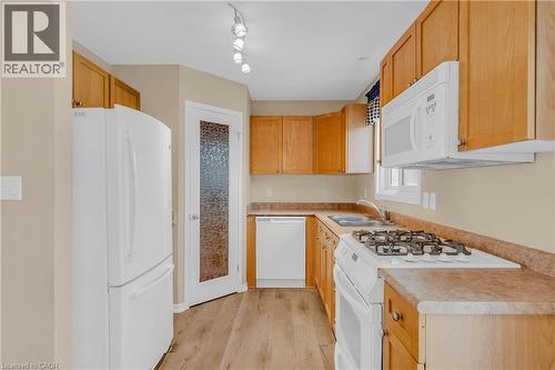 Kitchen with white appliances, light countertops, and light wood-style flooring - 33 Wellington S, Cambridge, ON - Indoor Photo Showing Kitchen With Double Sink