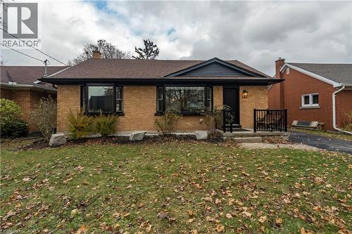 View of front facade with a front yard, brick siding, covered porch, a chimney, and roof with shingles - 266 Melrose Avenue, Kitchener, ON - Outdoor