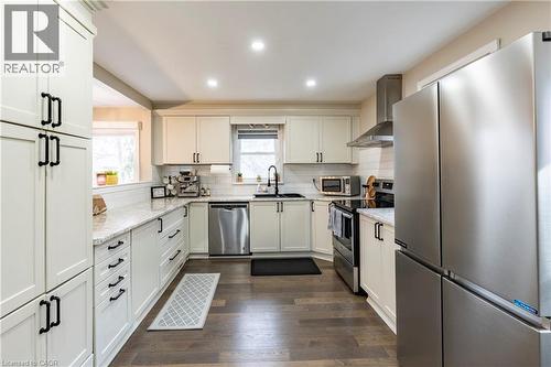 Kitchen with appliances with stainless steel finishes, wall chimney range hood, light stone counters, recessed lighting, and dark wood-style flooring - 266 Melrose Avenue, Kitchener, ON - Indoor Photo Showing Kitchen With Upgraded Kitchen