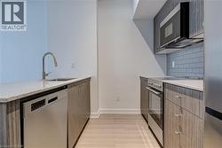 Kitchen featuring appliances with stainless steel finishes, a peninsula, backsplash, light stone countertops, and modern cabinets - 