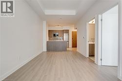 Unfurnished living room with light wood-type flooring and a tray ceiling - 