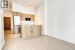 Kitchen featuring a peninsula, appliances with stainless steel finishes, modern cabinets, light wood-type flooring, and backsplash - 