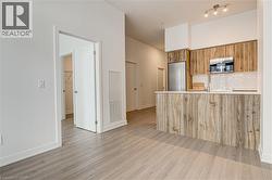 Kitchen with modern cabinets, brown cabinetry, tasteful backsplash, stainless steel appliances, and a peninsula - 