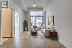 Living room with light wood finished floors and a raised ceiling - 