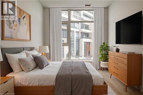 Bedroom featuring wood finished floors and a wall of windows - 25 Wellington Street A S Unit# 209, Kitchener, ON - Indoor Photo Showing Bedroom