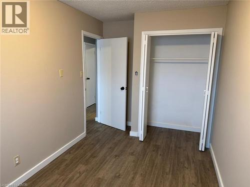 Unfurnished bedroom featuring a textured ceiling, dark wood-style floors, and a closet - 316 Dufferin Street, Stratford, ON - Indoor Photo Showing Other Room