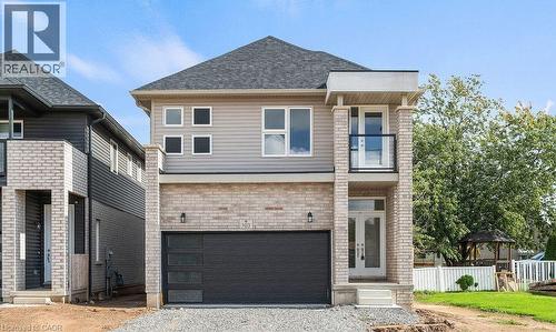 View of front of home with a balcony, brick siding, gravel driveway, a shingled roof, and a garage - 103 Mclaughlin Street, Welland, ON - Outdoor With Facade
