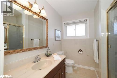 Bathroom featuring a shower stall, vanity, tile walls, light tile patterned floors, and a wainscoted wall - 86 Overlea Crescent Unit# Main, Waterloo, ON - Indoor Photo Showing Bathroom