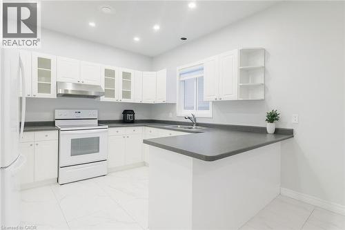 Kitchen with a peninsula, white appliances, white cabinetry, open shelves, and recessed lighting - 235 Pineland Court Unit# Upper, Waterloo, ON - Indoor Photo Showing Kitchen