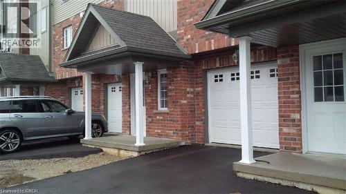 Property entrance with a garage, brick siding, asphalt driveway, and roof with shingles - 55 Mooregate Crescent Unit# 3, Kitchener, ON - Outdoor With Exterior