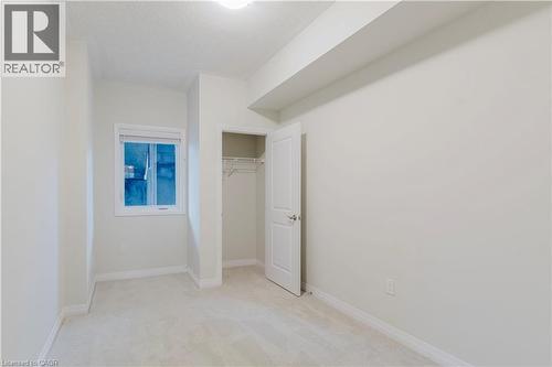 Unfurnished bedroom featuring a closet, light colored carpet, baseboards, and a textured ceiling - 25 Isherwood Avenue Unit# G105, Cambridge, ON - Indoor Photo Showing Other Room