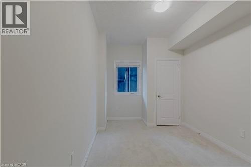 Spare room featuring light carpet, baseboards, and a textured ceiling - 25 Isherwood Avenue Unit# G105, Cambridge, ON - Indoor Photo Showing Other Room