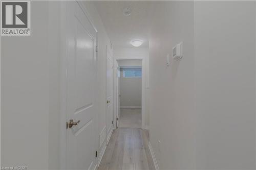 Corridor with a textured ceiling, light wood finished floors, and baseboards - 25 Isherwood Avenue Unit# G105, Cambridge, ON - Indoor Photo Showing Other Room