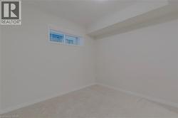 Unfurnished room featuring light carpet and baseboards - 