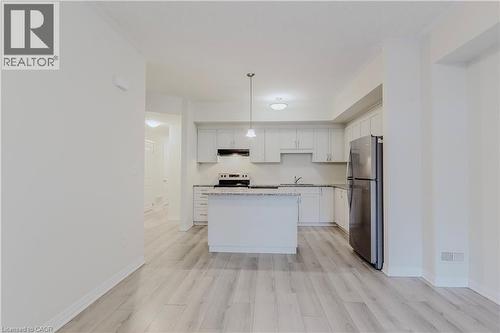 Kitchen featuring freestanding refrigerator, a center island, under cabinet range hood, a sink, and range with electric stovetop - 25 Isherwood Avenue Unit# G105, Cambridge, ON - Indoor Photo Showing Kitchen With Stainless Steel Kitchen