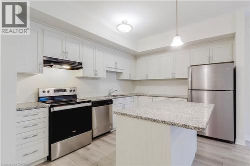 Kitchen with light wood-type flooring, light stone counters, under cabinet range hood, stainless steel appliances, and a sink - 25 Isherwood Avenue Unit# G105, Cambridge, ON - Indoor Photo Showing Kitchen With Stainless Steel Kitchen With Upgraded Kitchen