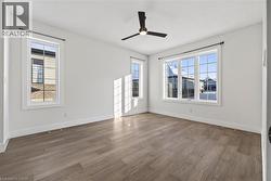 Spare room with wood finished floors, a ceiling fan, and healthy amount of natural light - 