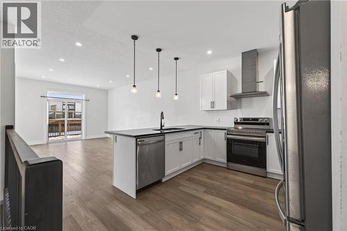 Kitchen with stainless steel appliances, wall chimney range hood, a peninsula, open floor plan, and white cabinetry - 7 South Court Street W, Norwich, ON - Indoor Photo Showing Kitchen With Stainless Steel Kitchen With Upgraded Kitchen