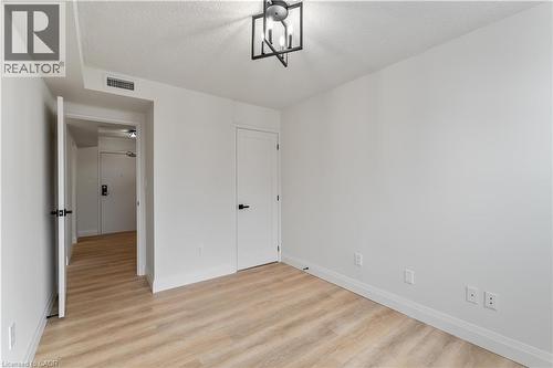 Unfurnished bedroom with light wood-type flooring and a textured ceiling - 120 Duke Street Unit# 905, Hamilton, ON - Indoor Photo Showing Other Room